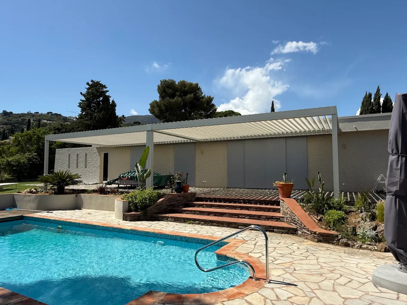 Pergola bioclimatique blanche au bord d’une piscine